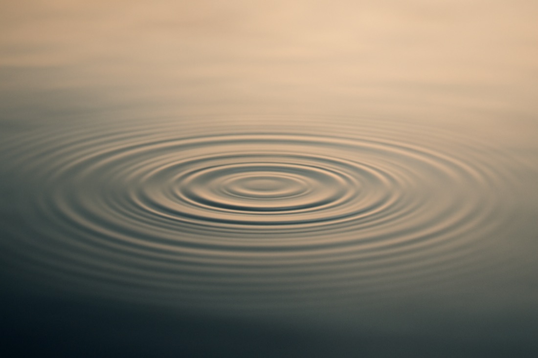 Gentle ripples settling on the calm surface of still water in soft light.